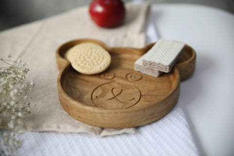 3. Wooden bear-shaped plate with cookies and wafers, placed on beige cloth with decorative flowers