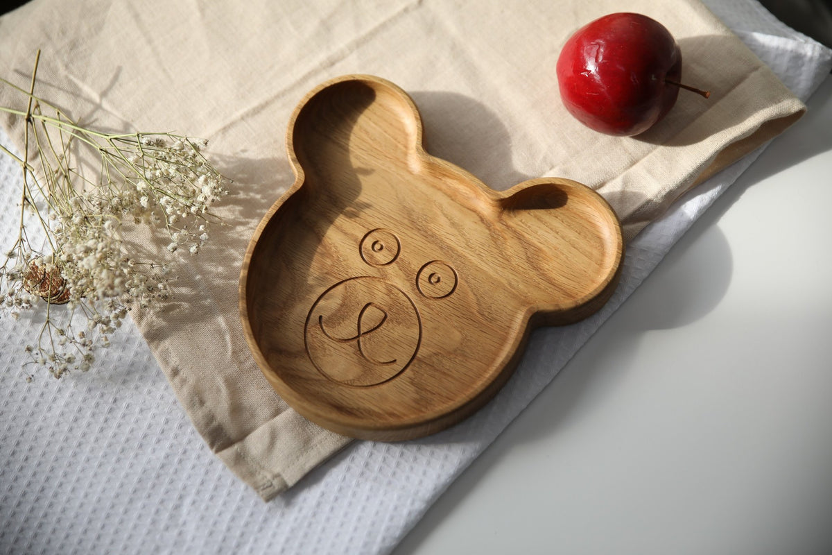 7. Wooden bear-shaped plate on beige cloth with red apple, showcasing smooth finish