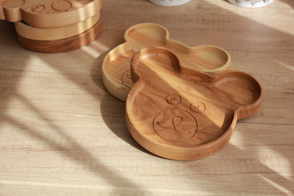 5. Two wooden bear-shaped plates stacked on wooden surface, highlighting engraved face design