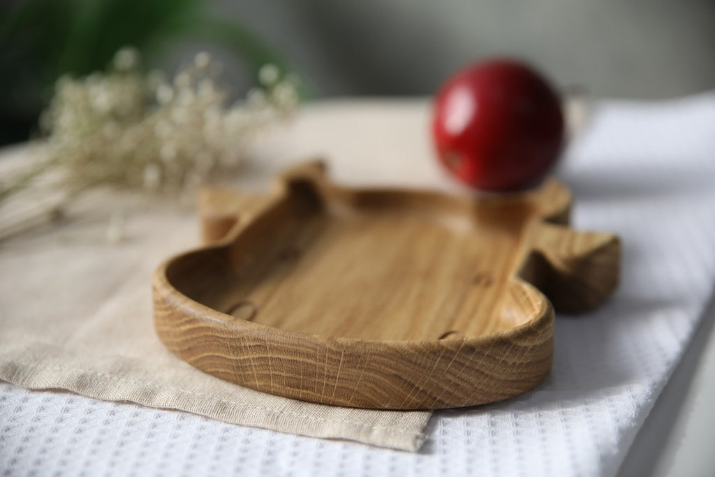 7. Side view of wooden bull-shaped plate on textured fabric with red apple