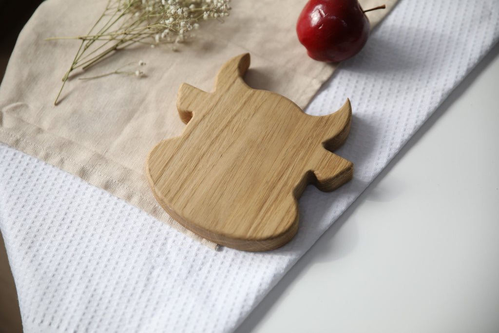 6. Wooden bull-shaped plate on white and beige fabric with red apple