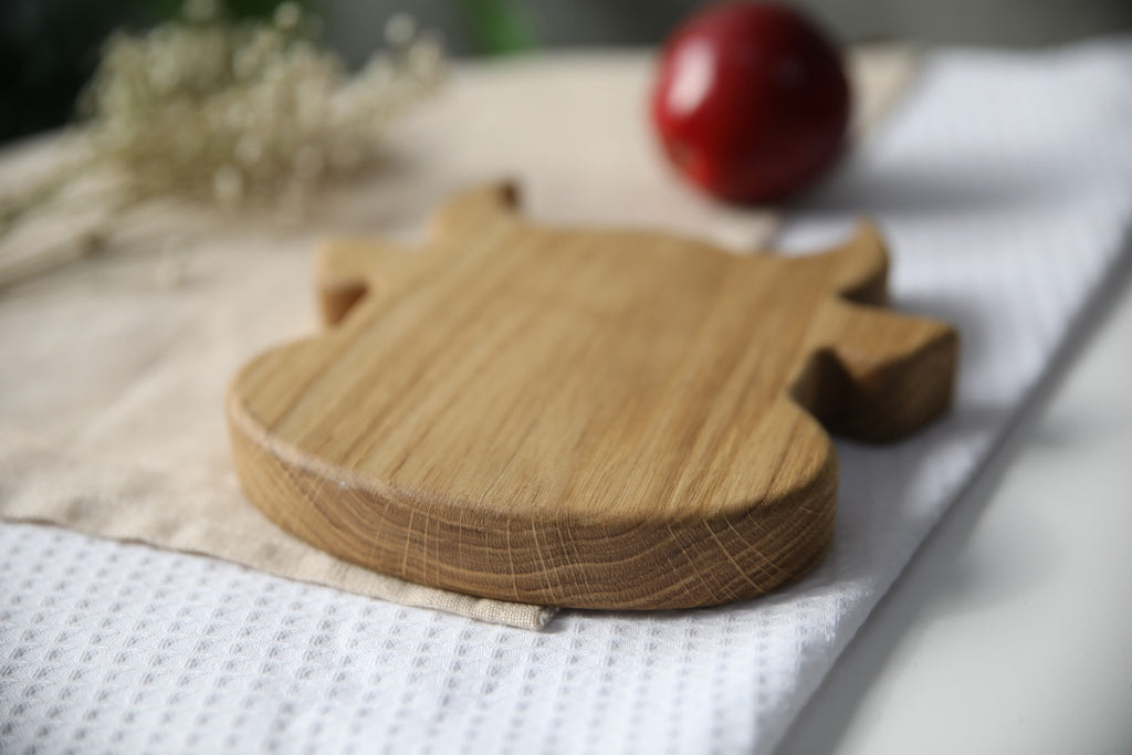 5. Back view of wooden bull-shaped plate on white and beige fabric with red apple