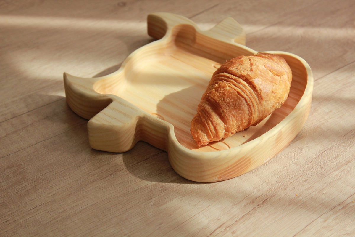 2. Wooden bull-shaped plate with croissant on light wood surface