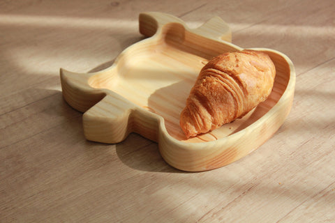 2. Wooden bull-shaped plate with croissant on light wood surface
