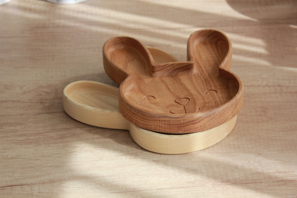 2. Stacked wooden bunny plates in oak and ash on a light wood surface
