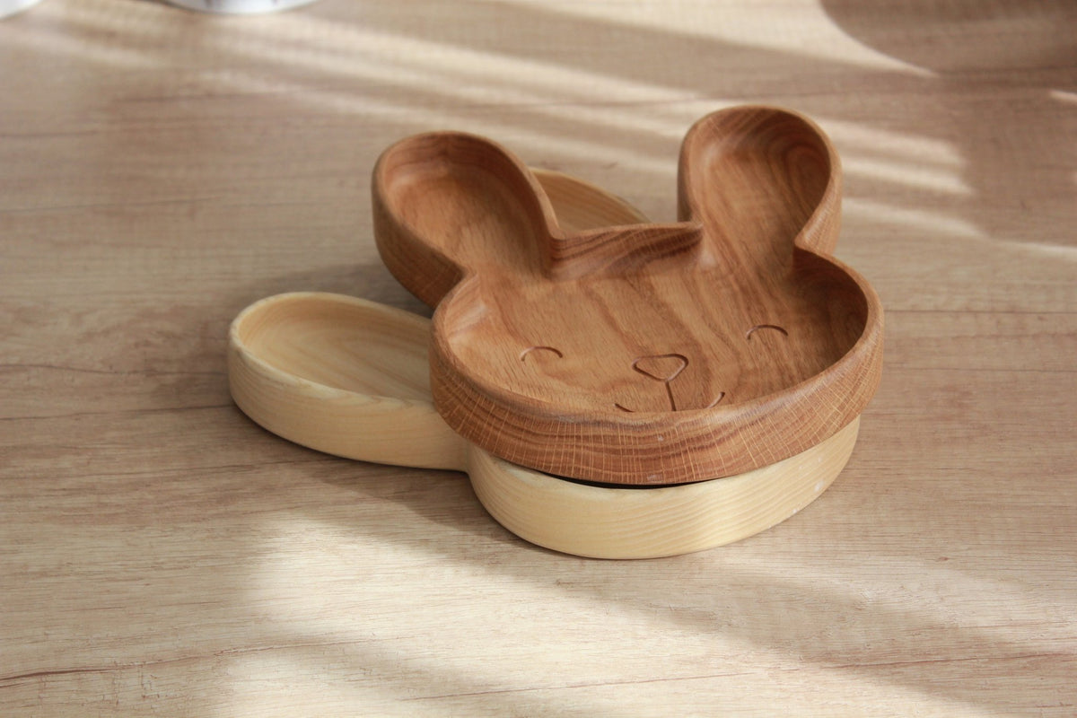 2. Stacked wooden bunny plates in oak and ash on a light wood surface