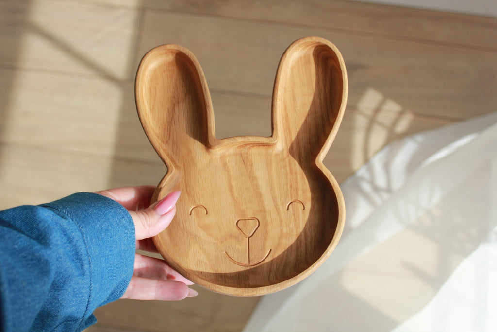 5. Hand holding an oak wooden bunny plate with a smiling face design