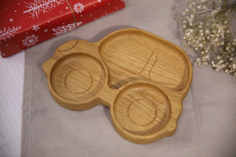 3. Wooden car-shaped plate for kids on a festive background with red gift wrap and flowers, highlighting its smooth finish