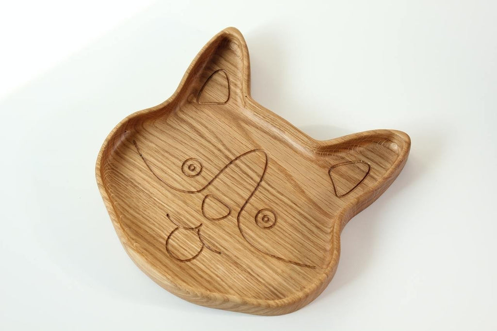 4. Angled view of corgi-shaped wooden plate for kids, emphasizing the engraved face details and smooth surface