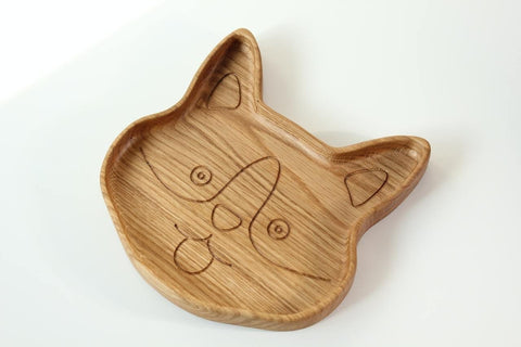 4. Angled view of corgi-shaped wooden plate for kids, emphasizing the engraved face details and smooth surface