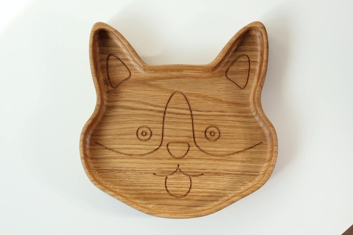 1. Handmade wooden plate for kids shaped like a corgi face, made from natural oak or ash wood, shown on a white background