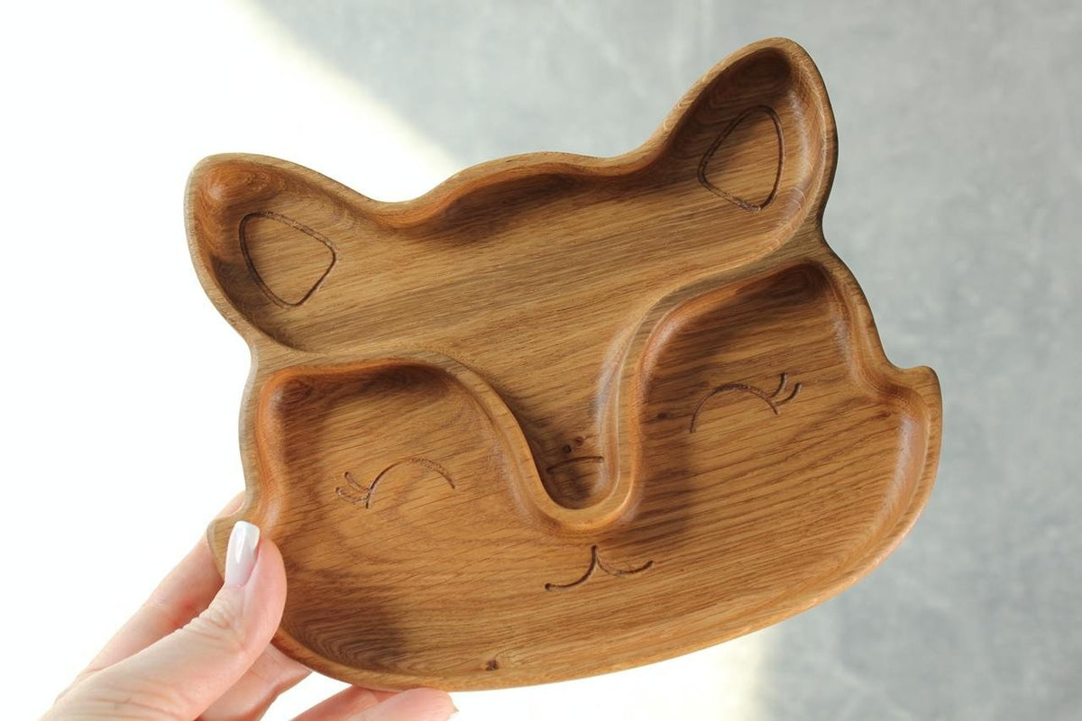 1. Handmade wooden fox-shaped plate with two sectors, crafted from oak or ash, held in hand against a neutral background