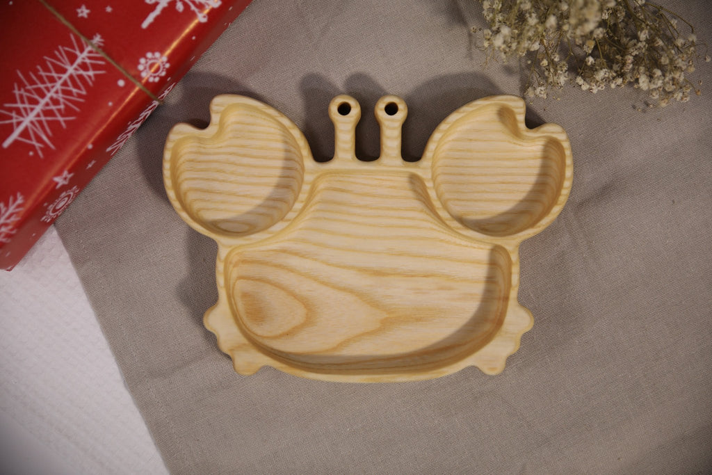 2. Light ash wood crab-shaped plate for kids on a textured fabric background, showcasing its natural color and smooth surface