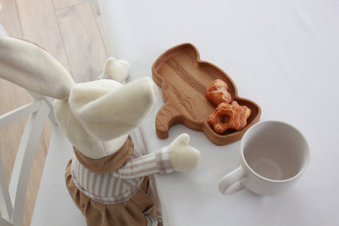 3. Wooden elephant-shaped plate with pastries next to a white mug and plush toy