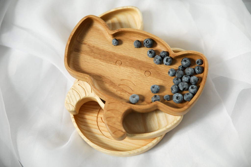 1. Handmade wooden elephant-shaped plate with blueberries on a white fabric background