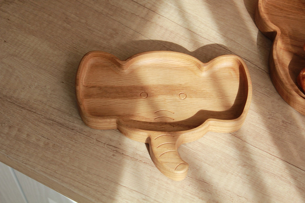 2. Wooden elephant-shaped plate on a wooden surface with natural light