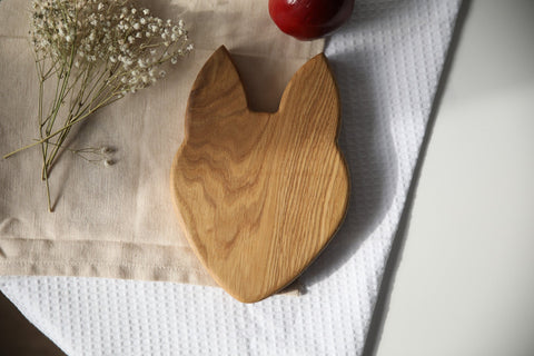 2. Back view of wooden fox-shaped plate on beige cloth with red apple and white flowers