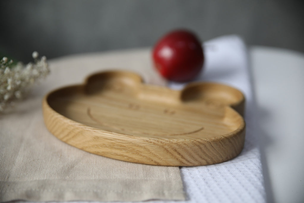 4. Side view of wooden frog plate on beige fabric with red apple, emphasizing thickness and smooth edges