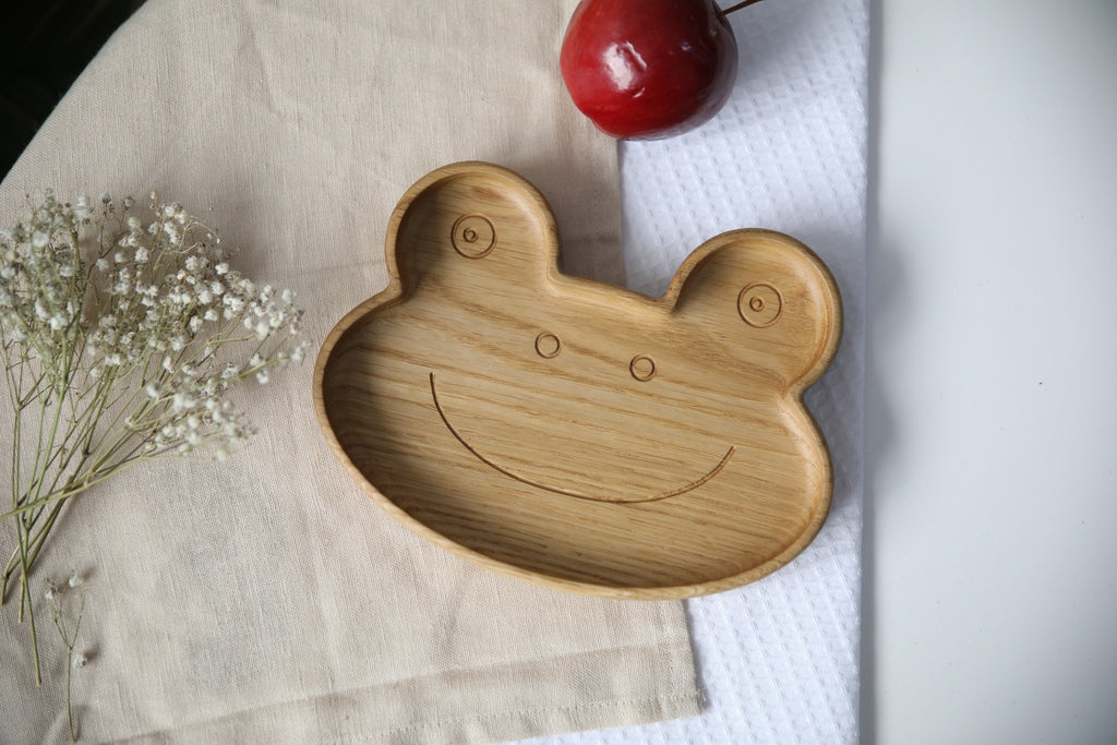1. Handmade wooden frog-shaped plate on beige fabric with red apple and white flowers, showcasing smooth finish