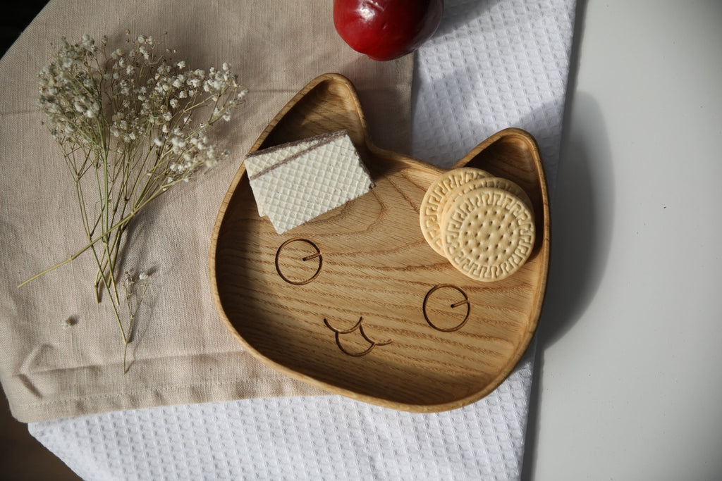 1. Wooden cat-shaped plate with cookies and wafers on a cloth with flowers and an apple