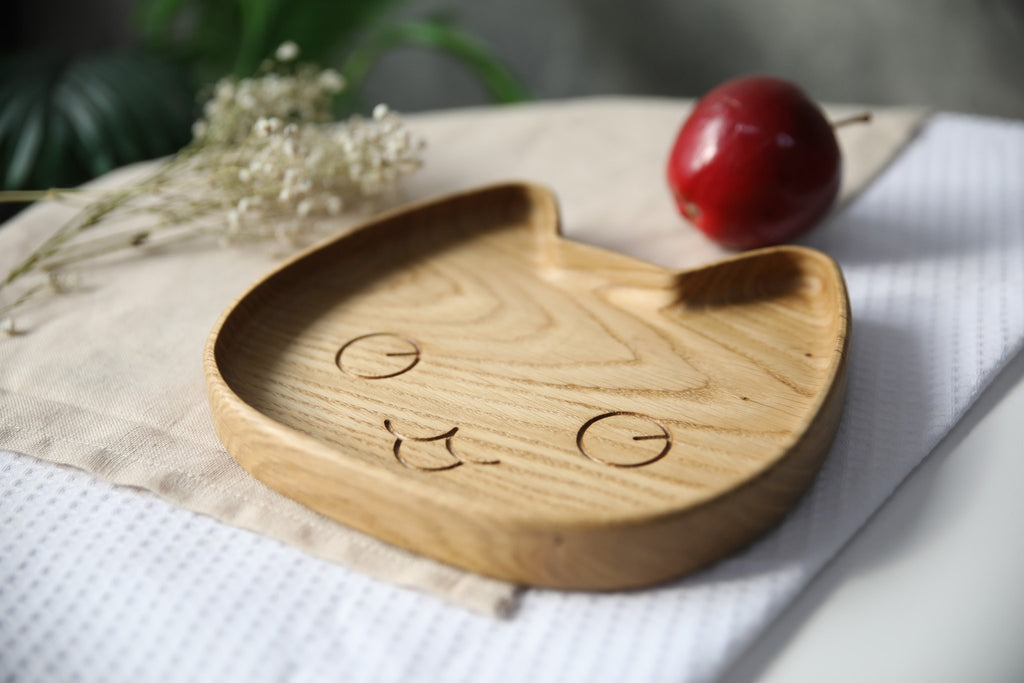 1. Wooden cat-shaped plate for kids on a cloth with flowers and an apple, showing smooth oak texture