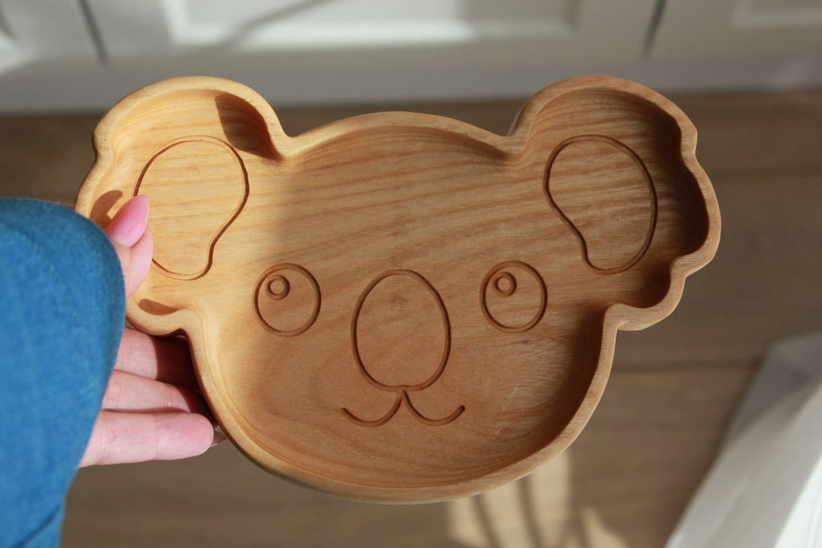 3. Close-up of wooden koala-shaped plate held in hand, showing detailed engraving and smooth finish