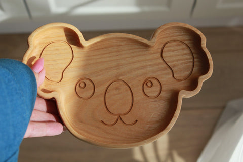 3. Close-up of wooden koala-shaped plate held in hand, showing detailed engraving and smooth finish