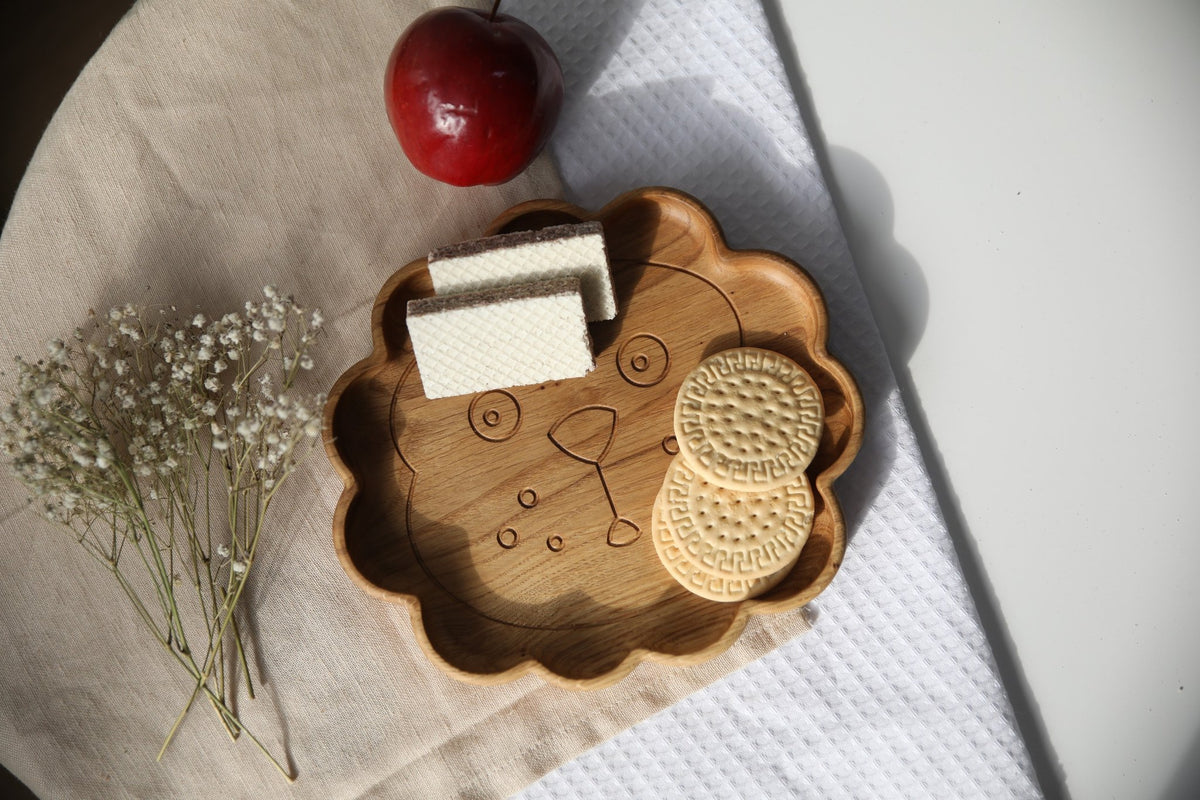 7. Wooden lion-shaped plate with cookies and apple on a cloth, highlighting natural wood texture