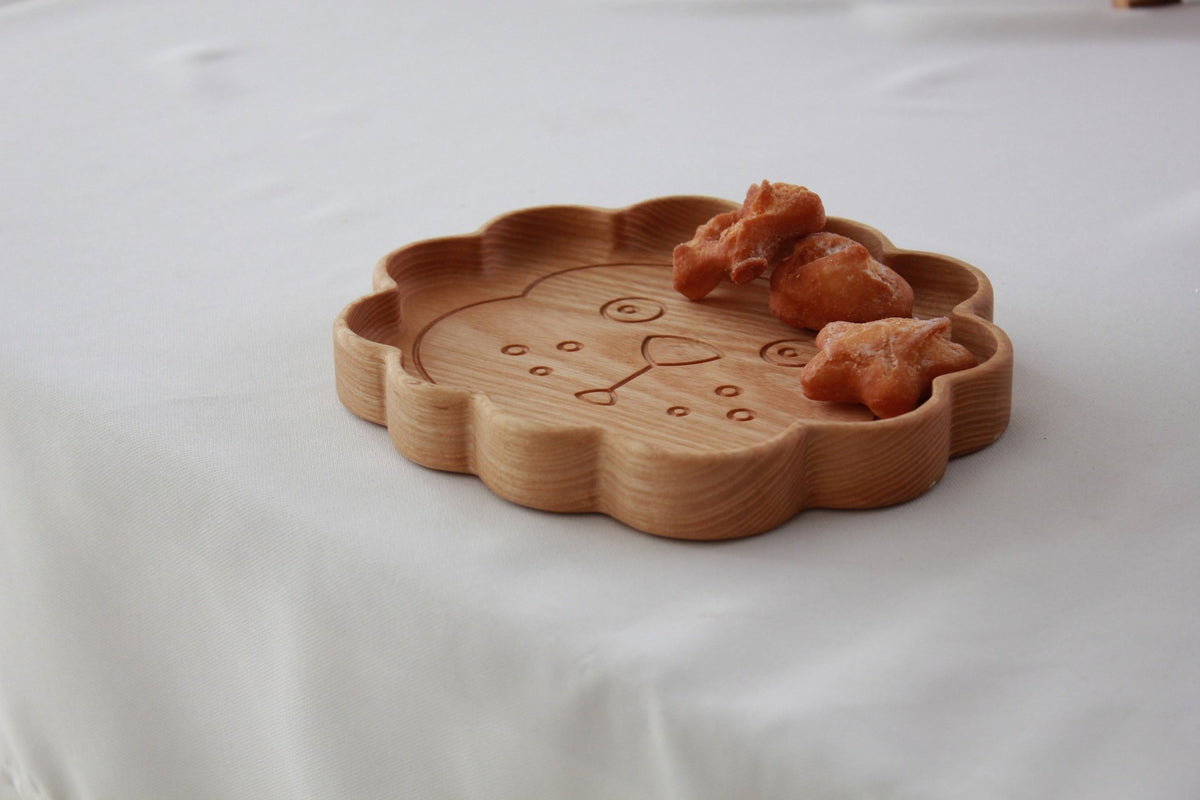 2. Wooden lion-shaped plate with snacks on a white table, highlighting natural wood grain