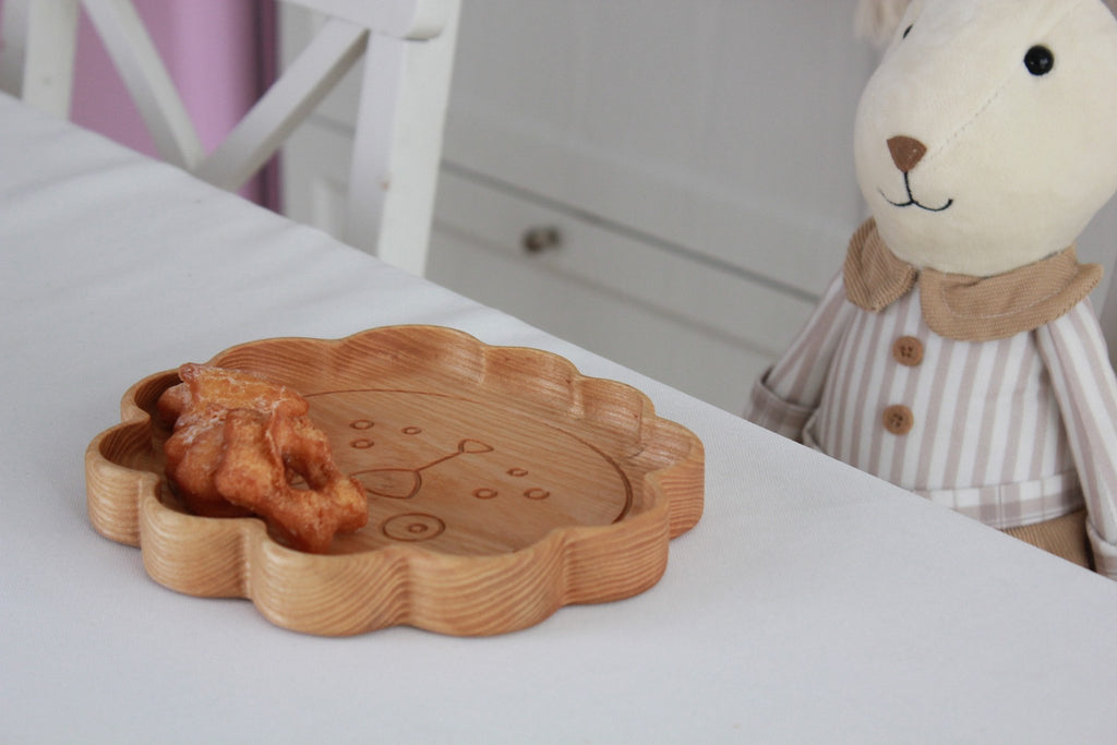 6. Wooden lion-shaped plate with snacks on a table next to a plush toy, showcasing child-friendly design