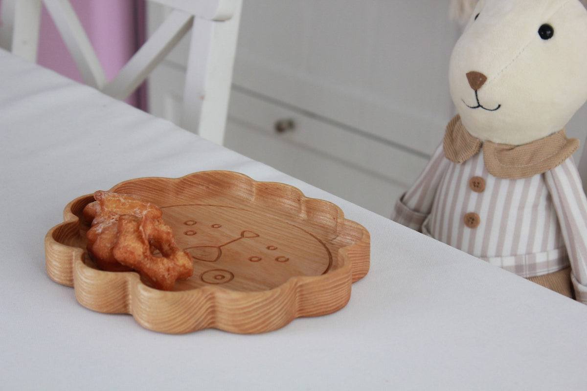 6. Wooden lion-shaped plate with snacks on a table next to a plush toy, showcasing child-friendly design
