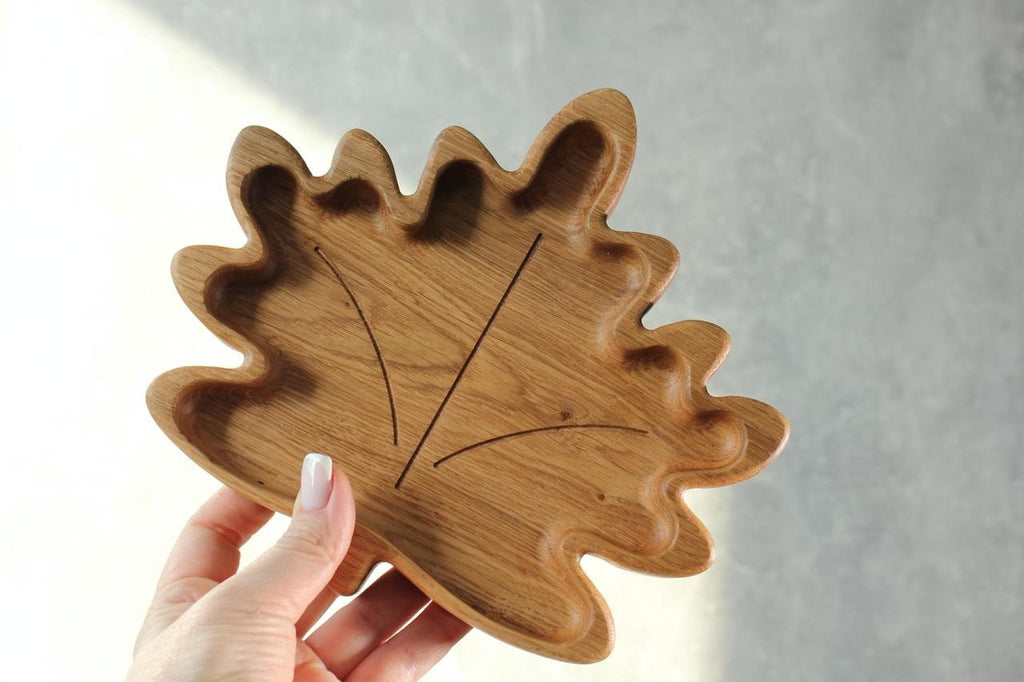 1. Person holding a wooden plate for kids in maple leaf shape, highlighting the smooth finish and natural wood texture