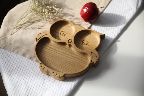5. Side view of wooden owl-shaped plate on a white and beige cloth, highlighting depth and smooth finish