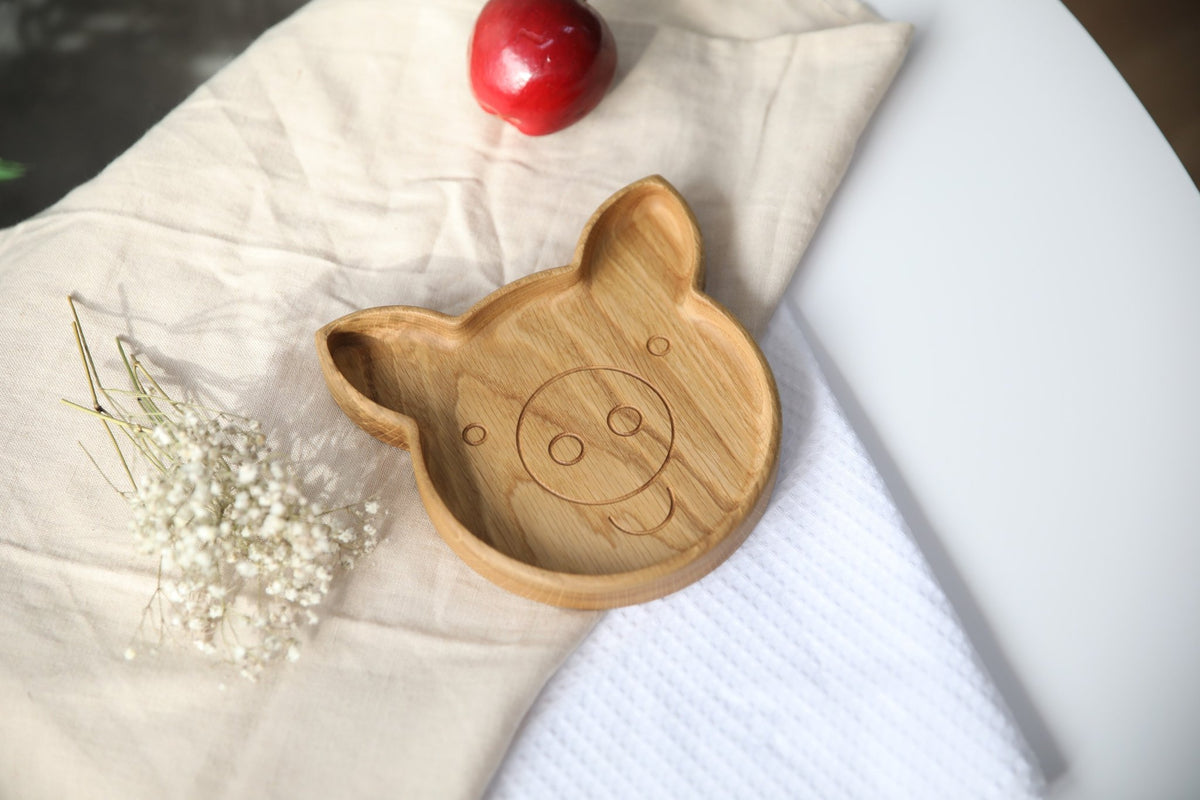 5. Wooden pig-shaped plate on a white and beige fabric with a red apple and flowers