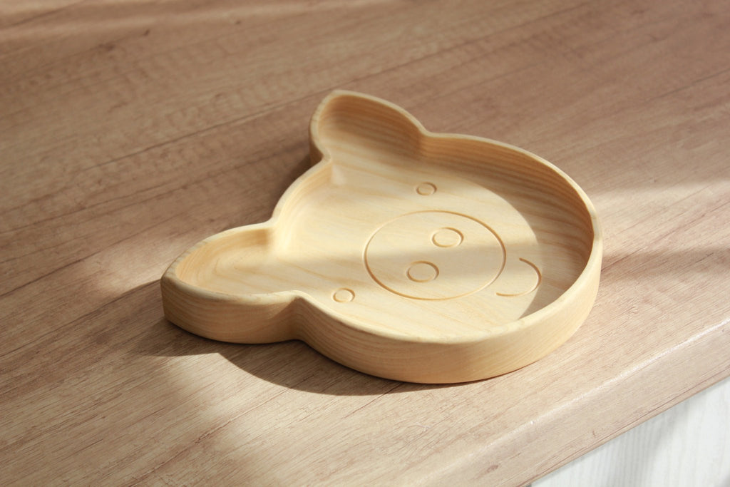 7. Light wood pig-shaped plate on wooden surface, shown from side angle