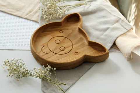 3. Side view of wooden pig-shaped plate on a table with light fabric and flowers
