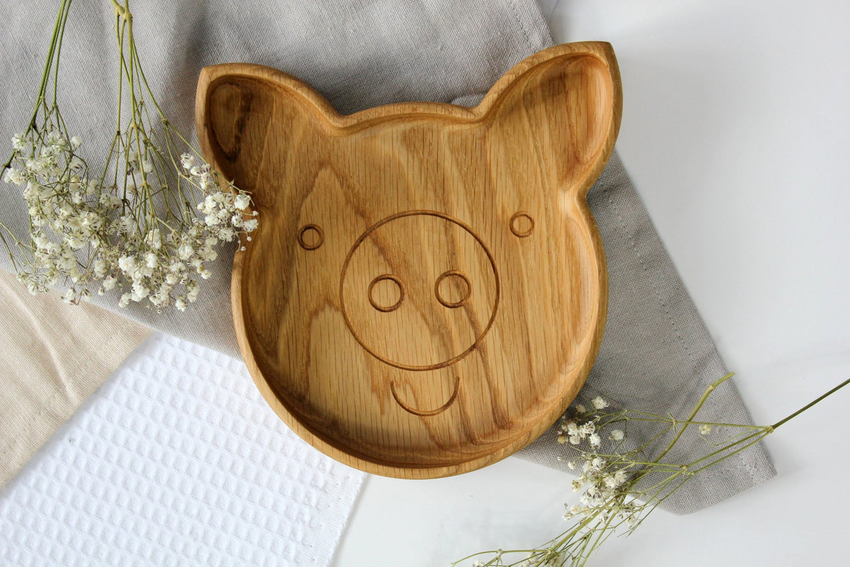 1. Handmade wooden pig-shaped plate on a light fabric with flowers, showcasing smooth oak finish