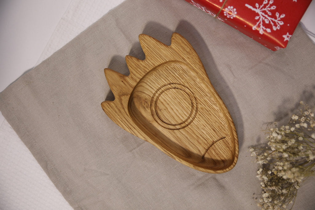 2. Wooden rocket-shaped plate for kids on a beige cloth with a red gift box and flowers, showcasing its natural oak or ash material
