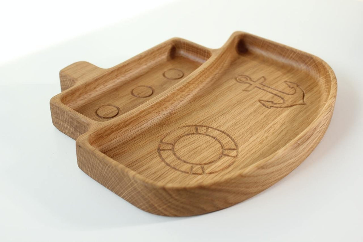 4. Angled view of wooden ship-shaped plate for kids with engraved nautical motifs, crafted from oak or ash, on a white background