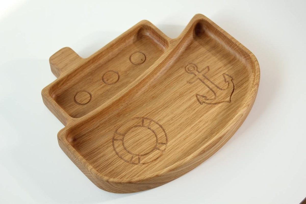 2. Side view of wooden ship-shaped kids' plate with engraved nautical designs, crafted from oak or ash, on a white background