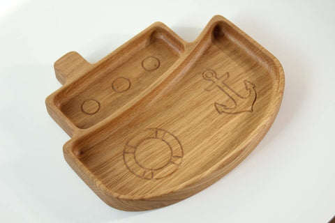 2. Side view of wooden ship-shaped kids' plate with engraved nautical designs, crafted from oak or ash, on a white background