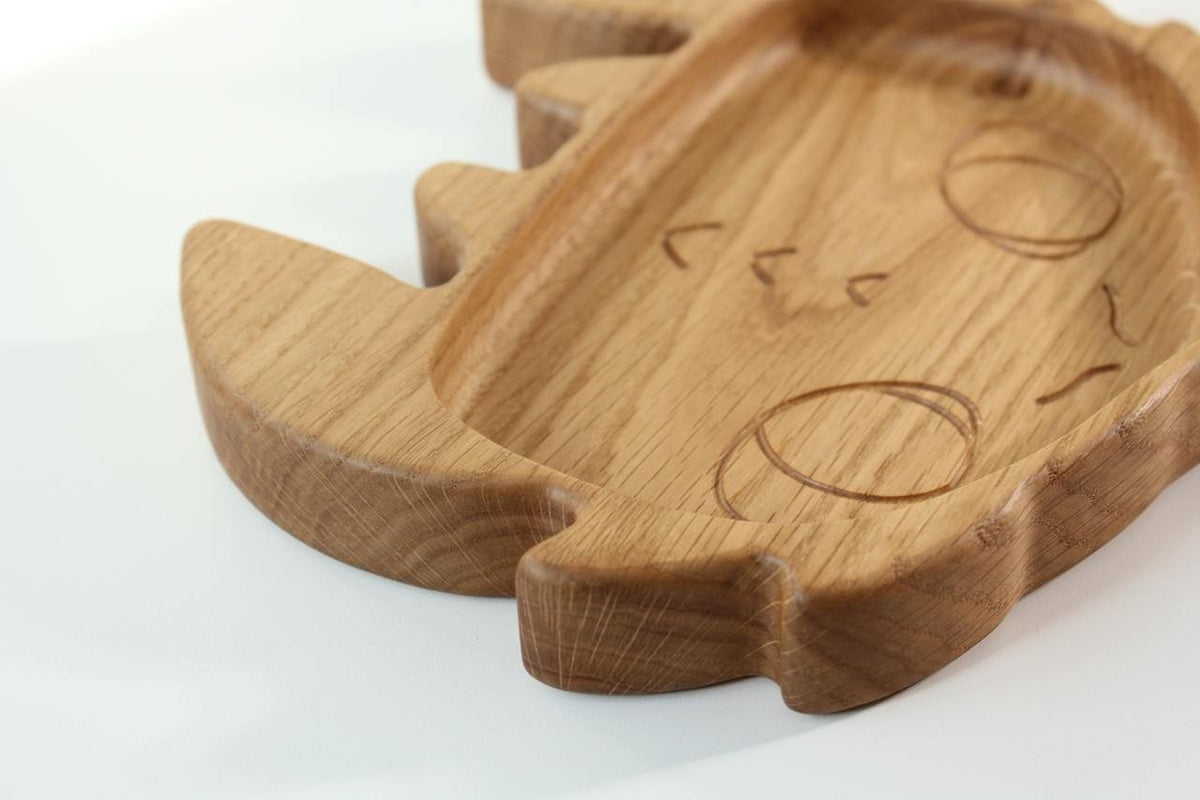 5. Detail shot of the edge and surface of a handmade wooden kids plate shaped like a character face, crafted from oak wood