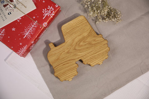 3. Back view of wooden tractor-shaped plate on beige cloth, showing natural wood grain and smooth finish