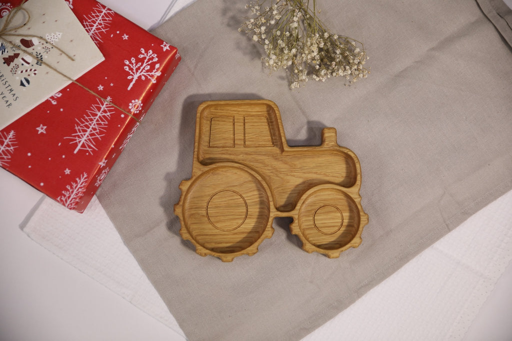 1. Handmade wooden tractor-shaped plate on a beige cloth with red gift box and flowers, showcasing natural oak or ash wood finish