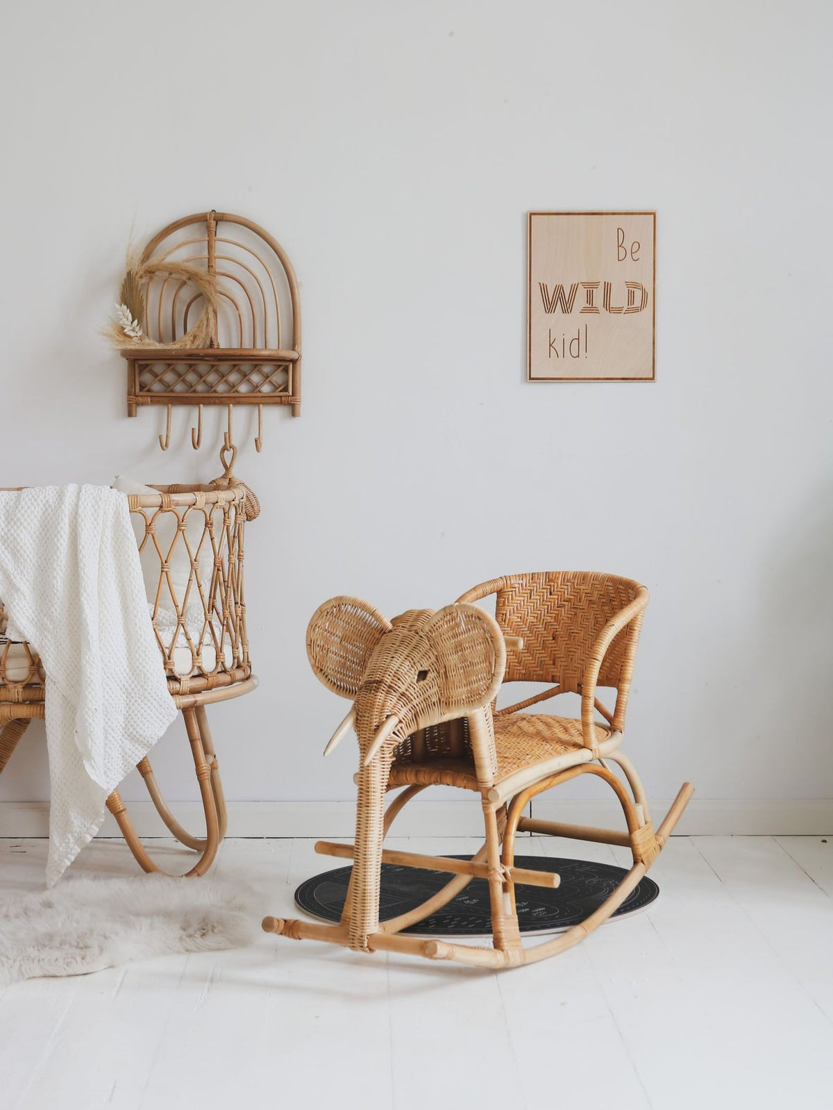 2. Nursery with wooden poster 'Be Wild Kid' on wall, elephant rocking chair, and wicker crib