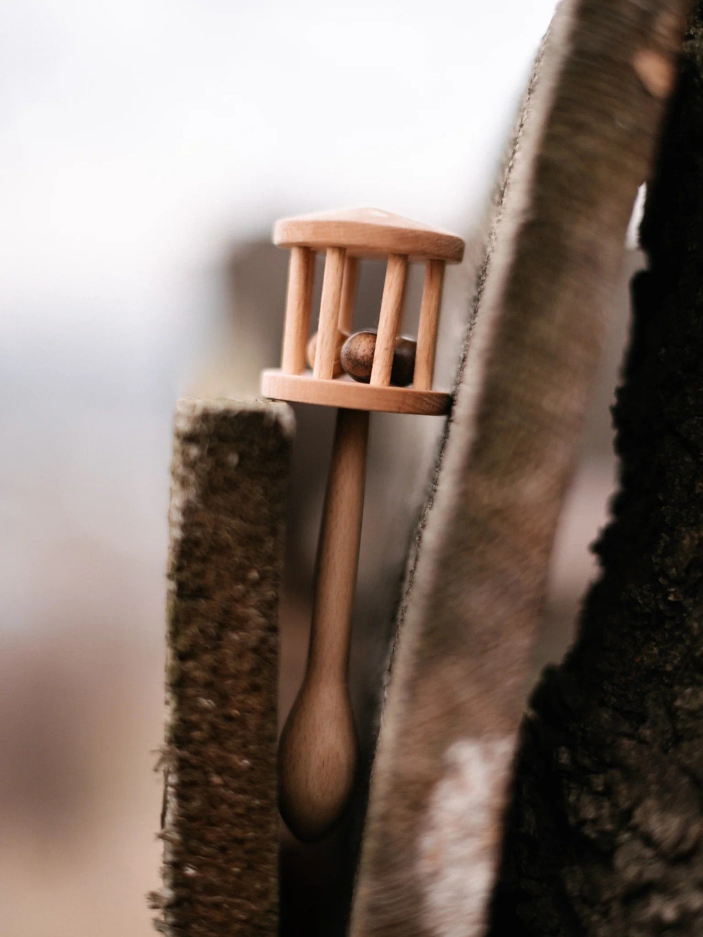 6. Wooden Story rattle placed between two pieces of wood outdoors