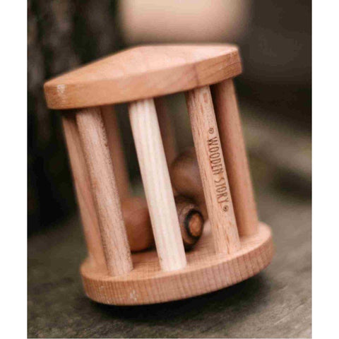1. Close-up of Wooden Story Turtle Dove rattle on a natural surface, showcasing the brand logo and wooden texture