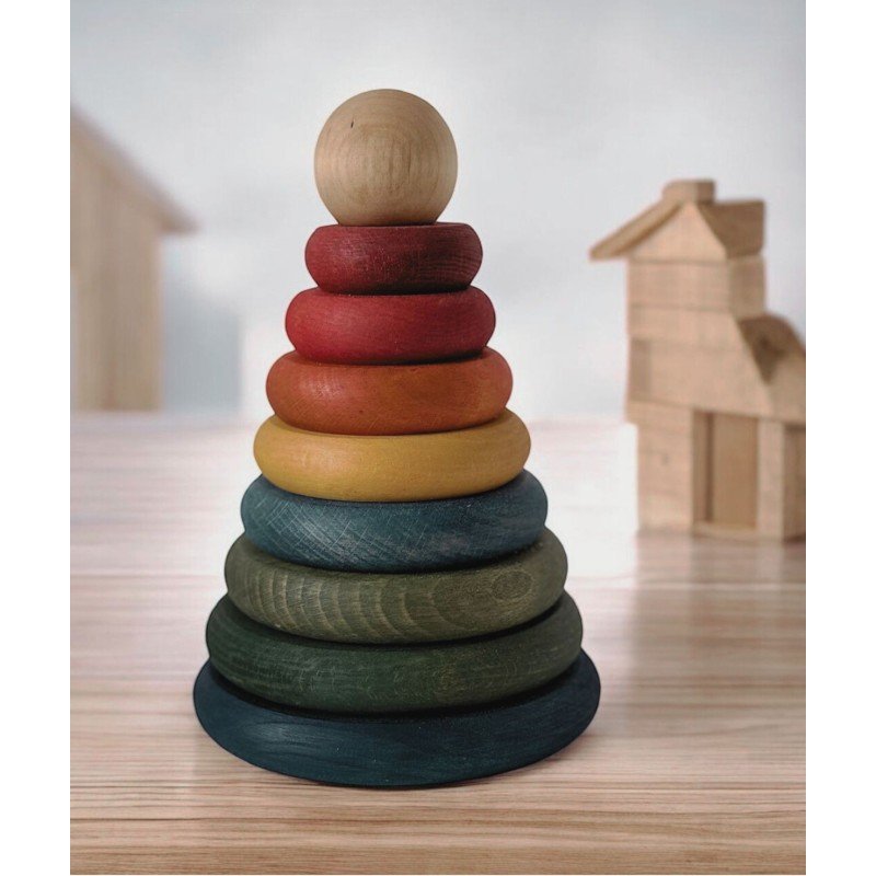 1. Wooden round pyramid toy with colorful disks stacked on a wooden table, with blurred wooden blocks in the background