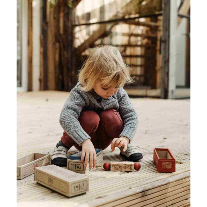 6. Child playing with Wooden Story spinning puzzle on a wooden deck with boxes around