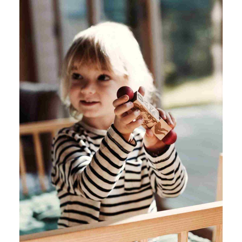 8. Smiling child holding a Wooden Story spinning puzzle with red ends in a bright room